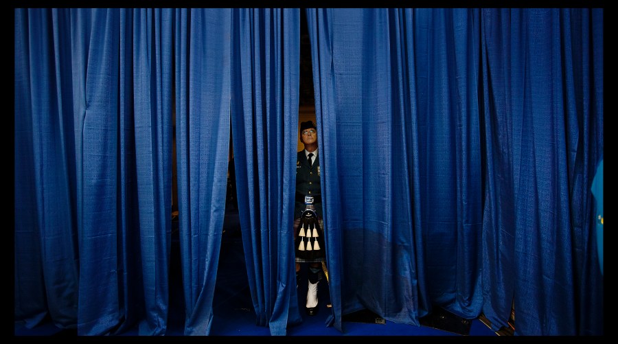 Canadian bag piper watches the 2013 Ford World Curling Championships from behind a curtain