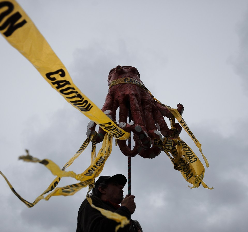 A Protesters holds up a paper cache octopus prior to Canada's Prime Minister Justin Trudeau, meeting with Canadian coast guard workers in Victoria